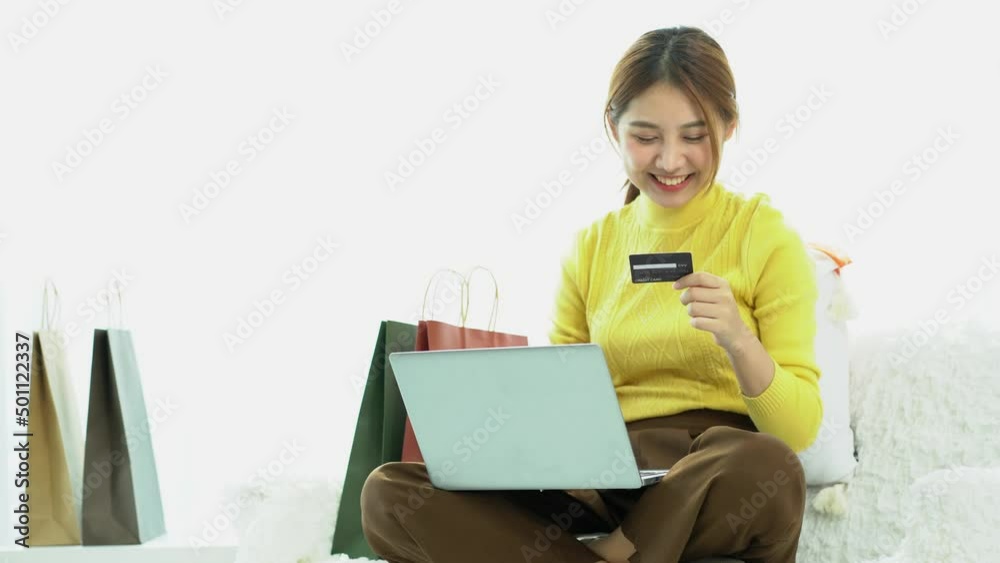 Beautiful Asian girl shopping online with a credit card and smiling. Women using laptops and doing online transactions Over the Internet, online shopping ideas with a credit card at home. Beautiful Asian girl shopping online with a credit card and smiling. Women using laptops and doing online transactions Over the Internet, online shopping ideas with a credit card at home.
