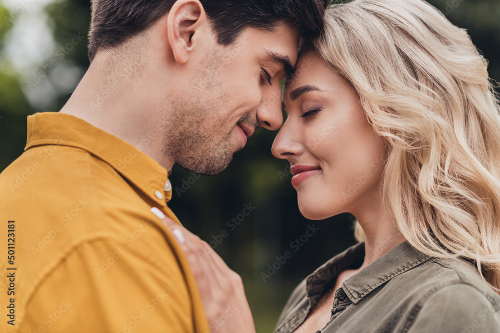 Cropped profile side view portrait of attractive sweet cheerful sweet couple enjoying cuddling on fresh air outdoors Cropped profile side view portrait of attractive sweet cheerful sweet couple enjoying cuddling on fresh air outdoors