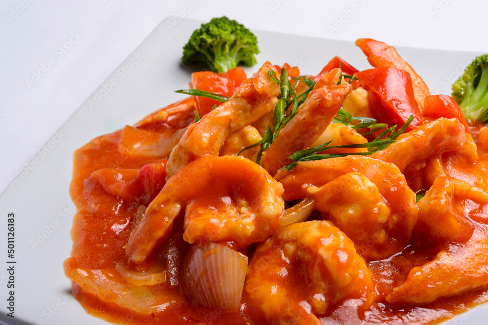 Shrimp in tomato sauce on a white square plate. Closeup. Chinese food.