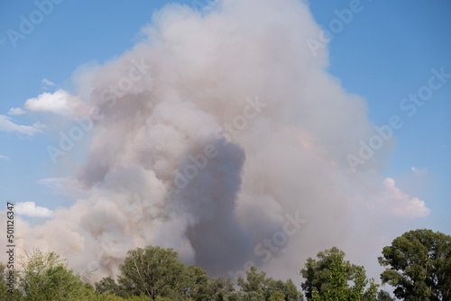 Smoke billowing into the air from a bush fire over dry farmland