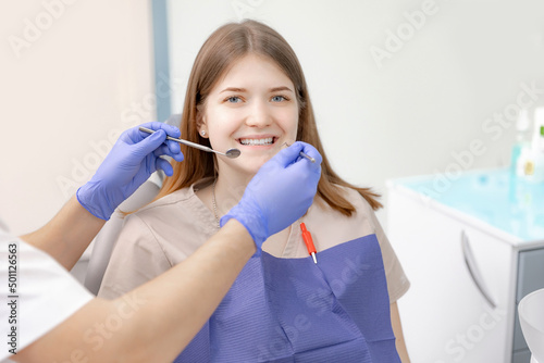 Happy young brunette woman at dentist checks her smile teeth