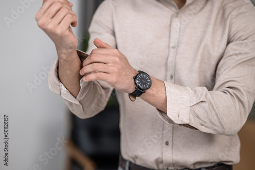 A man wearing a shirt and fastening cuffs