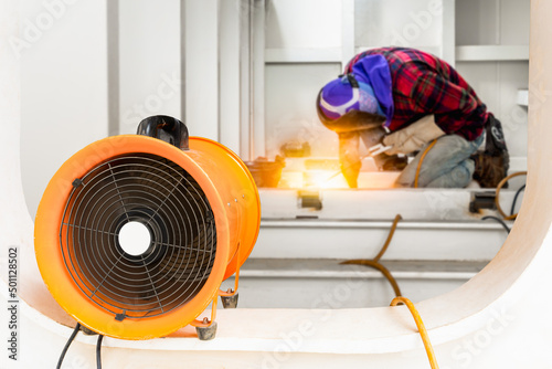 Mobile ventilation fan installed to ventilate air pollution in welding of structural steel working in confined spaces area at site construction. Ventilation system safety concept.
