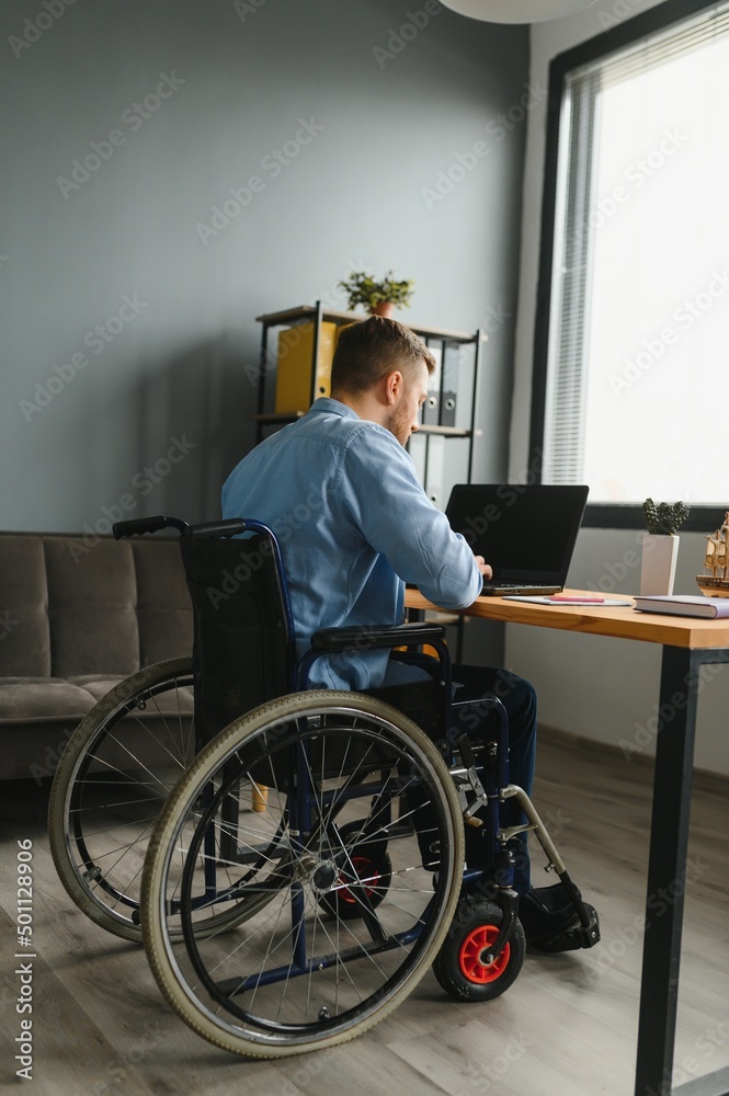 Young happy entrepreneur in wheelchair working on laptop at home. Young happy entrepreneur in wheelchair working on laptop at home.
