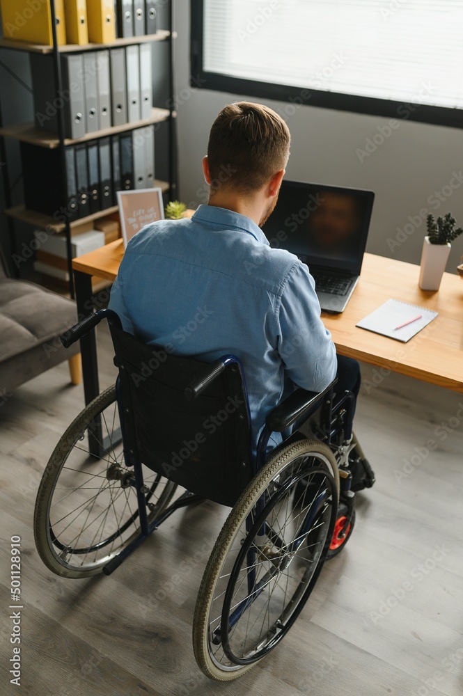 Handicapped Businessman Sitting On Wheelchair And Using Computer In Office Handicapped Businessman Sitting On Wheelchair And Using Computer In Office