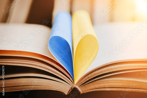 Close up opened book with blue and yellow heart shaped pages. Education in Ukraine concept photo