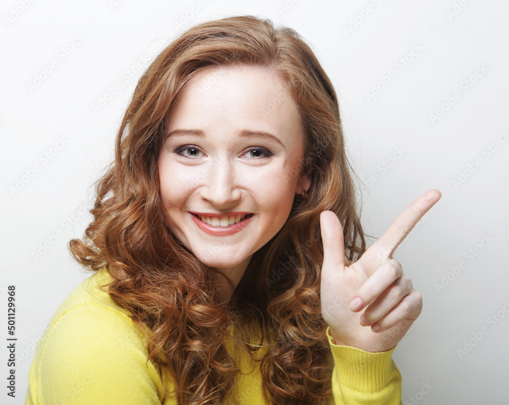 Smiling young woman pointing with finger at blank copy space aside Smiling young woman pointing with finger at blank copy space aside