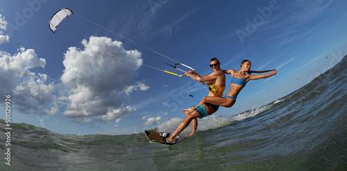 Lovely couple up on one kite board. Woman Riding On Kite surfer's Back and kiting on a sea photo