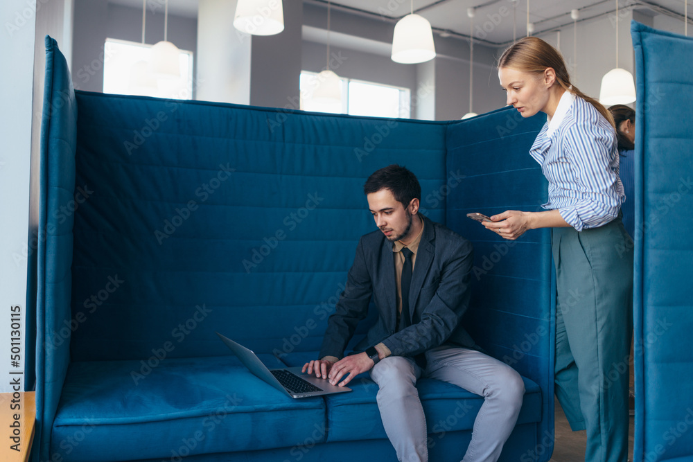 Woman standing by man working on his laptop. Woman standing by man working on his laptop.