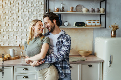 Satisfied young european male hugging his wife in modern kitchen interior. Love, relationship and romantic
