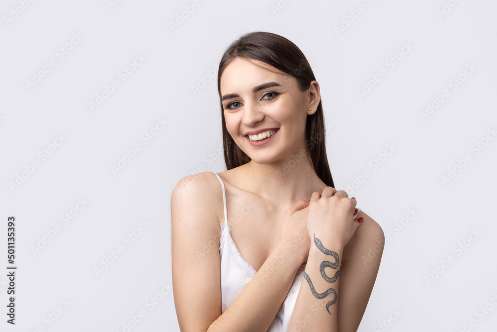 Obraz premium Beautiful smiling woman with clean skin, natural make-up and white teeth on a gray background