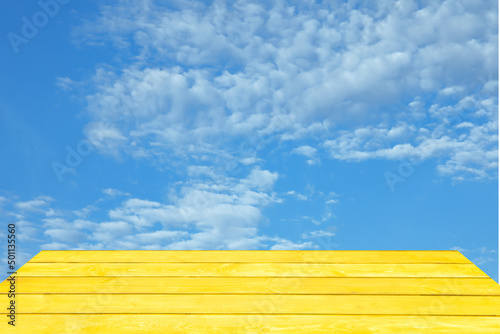 Empty yellow wooden table on the blue sky background