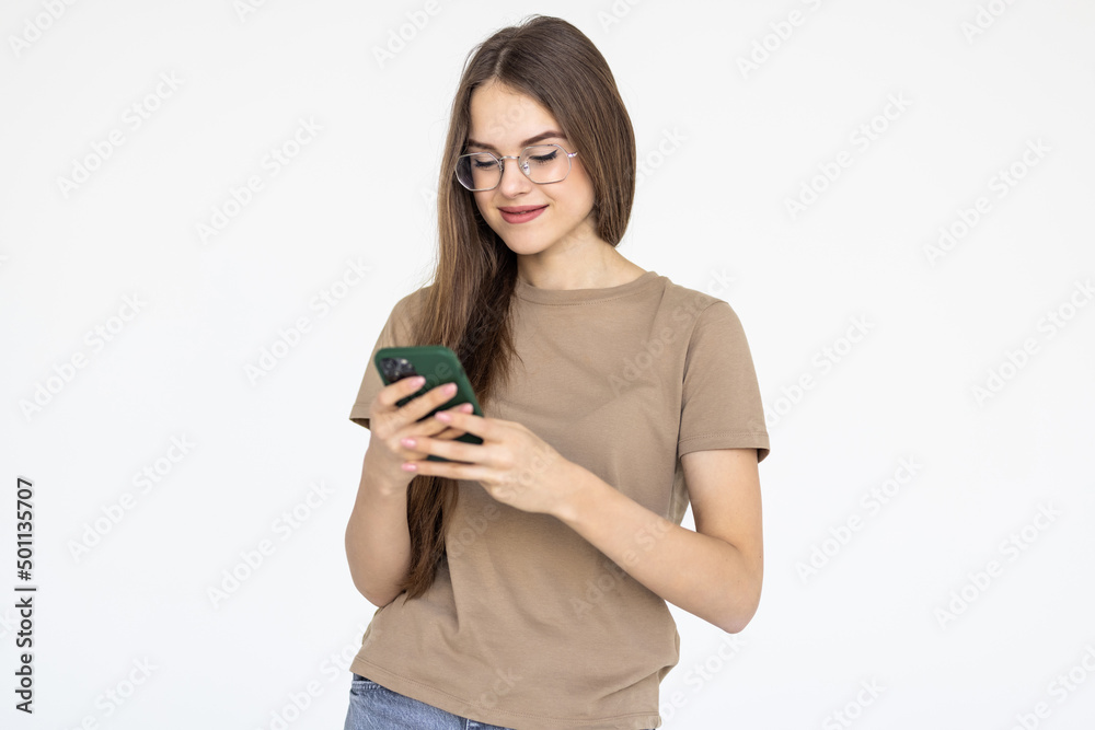 Pleased brunette woman in t-shirt writing message on smartphone isolated over white background Pleased brunette woman in t-shirt writing message on smartphone isolated over white background