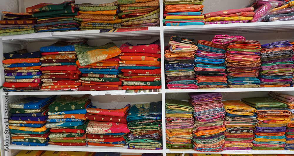 Colorful sarees or saris are arrange on racks and display in a retail shop, for use as indian textiles background.