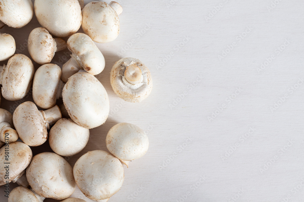 White fresh champignons on a white table with copy space