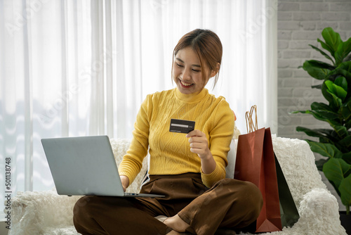 Easy and safe web shopping. Happy satisfied Asian lady buy goods use a credit card for secure payment in the trusted online store. Smiling female spend money on internet pay via bank application photo