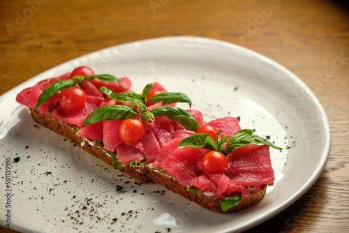 Bruschetta with red pickled meat on a white plate