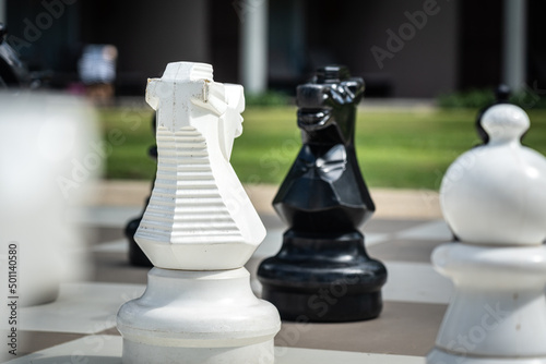 A giant peice of black horse is facing with white opposite site in the chess game. Business strategy successful concept scene. Close-up and selective focus at the object. photo