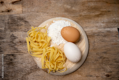 Basic ingredients for making pasta, eggs and flour on a wooden board