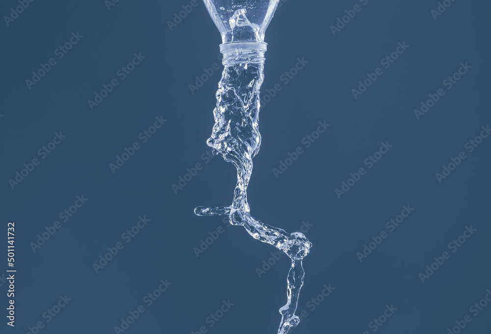 Splash of water from a bottle on a blue background. Reflection on the surface of the water. Splash of water from a bottle on a blue background. Reflection on the surface of the water.