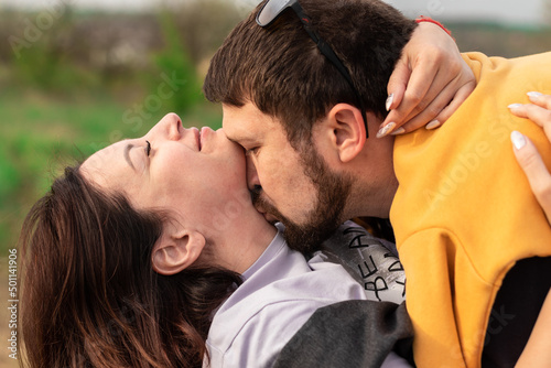 young man kisses his beloved on the neck outside