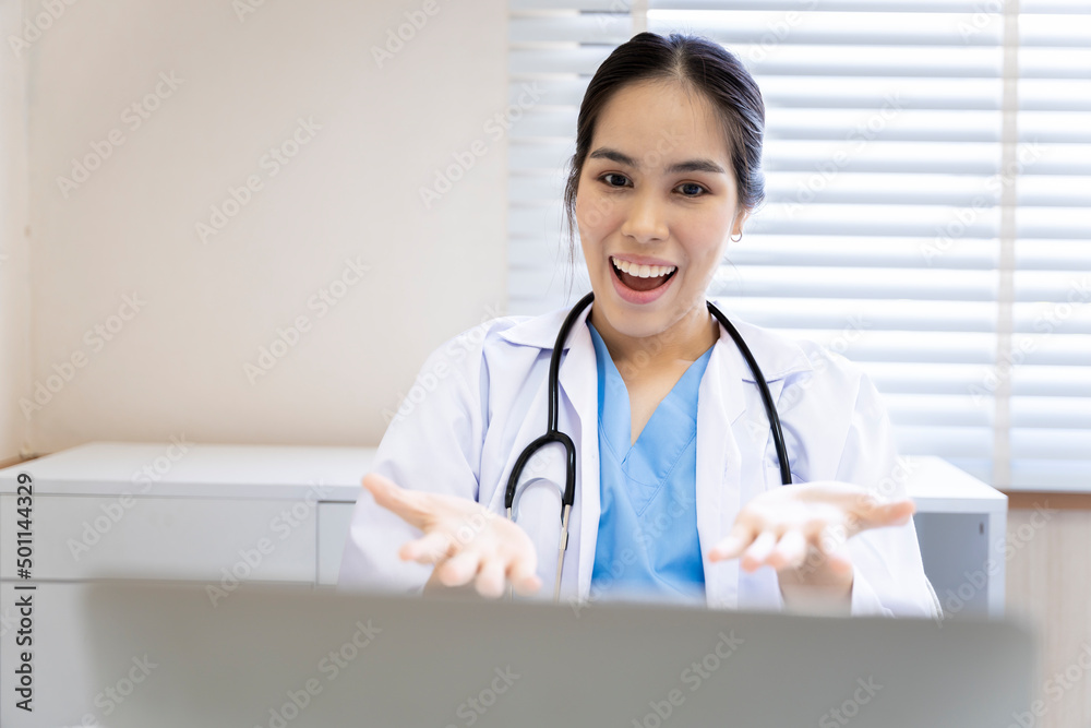 An Asian female doctor in Thailand is communicating with patients over the Internet with her personal laptop at the hospital to advise patients at home. An Asian female doctor in Thailand is communicating with patients over the Internet with her personal laptop at the hospital to advise patients at home.