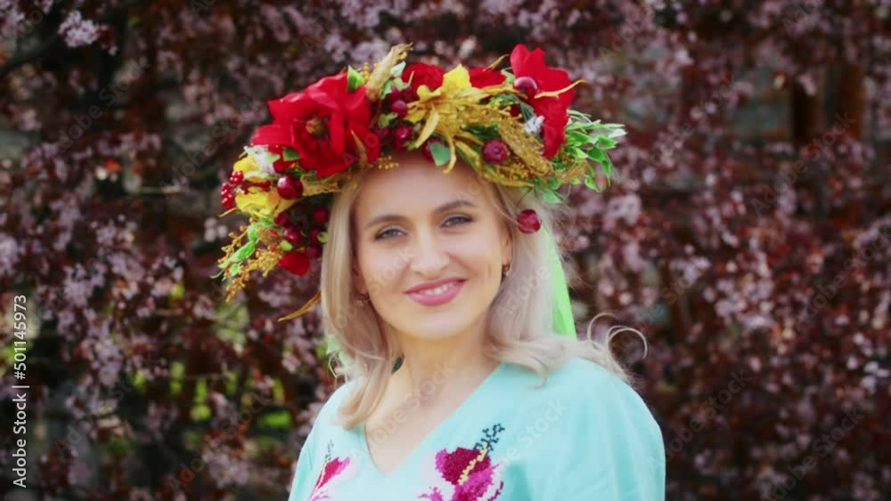 a happy woman in a wreath on her head rejoices against the backdrop of blooming pink sakura flowers. Weekend stroll with a smile at sunset. woman and spring. a happy woman in a wreath on her head rejoices against the backdrop of blooming pink sakura flowers. Weekend stroll with a smile at sunset. woman and spring.