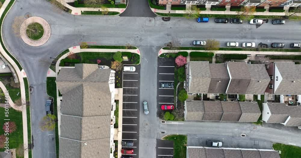Top down aerial of apartment building unit homes and car driving through residential community in USA. Trees blooming in spring season. Top down aerial of apartment building unit homes and car driving through residential community in USA. Trees blooming in spring season.