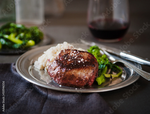 Filet Mignon with a Piece Pierced on a Fork; Served with Mashed Potatoes and Broccoli Rabe photo