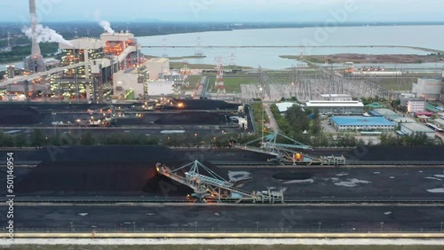 Tracking shot across coalfield and industrial ultra-supercritical coal-fired power plant with smokes raising from chimney located at lekir bulk terminal jalan, teluk rubiah, manjung, perak, malaysia. photo