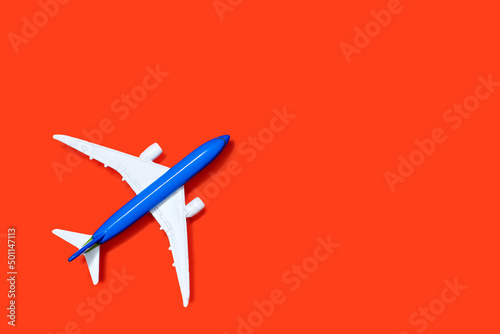 Aircraft model on a orange background with free space for text or advertising. Tourism or freight transport concept. Toy airplane on a red background with a top view