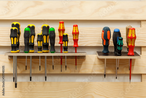 Screwdrivers in workshop. Set of Screw Drivers. Multicolored screwdrivers hanged on shelf.  photo
