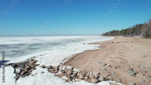flying over frozen sea bay bay on a sunny day blue sky coastline and rocks. High quality 4k footage