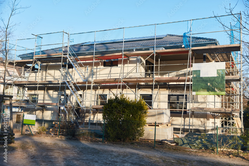 Baustelle auf Grundstück mit Mehrfamilienhaus und Gerüst