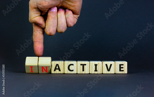 Active or inactive symbol. Businessman turns wooden cubes and changes the word Inactive to Active. Beautiful grey table grey background, copy space. Business and active or inactive concept.