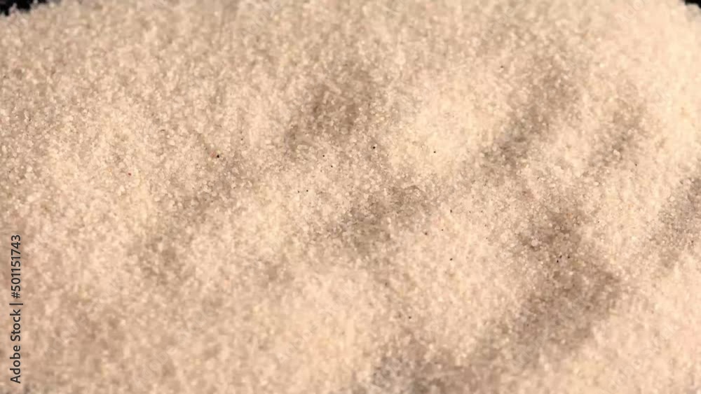 Golden sand blown by the wind from a dark surface