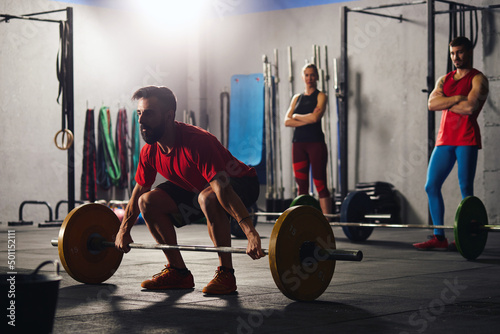 Man squatting and lifting a barbell.
