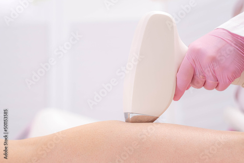 Diode laser hair removal, Beautician removes hair on beautiful female legs, Hair removal for smooth skin, laser procedure at beauty studio or clinic, Body care epilation treatment. photo