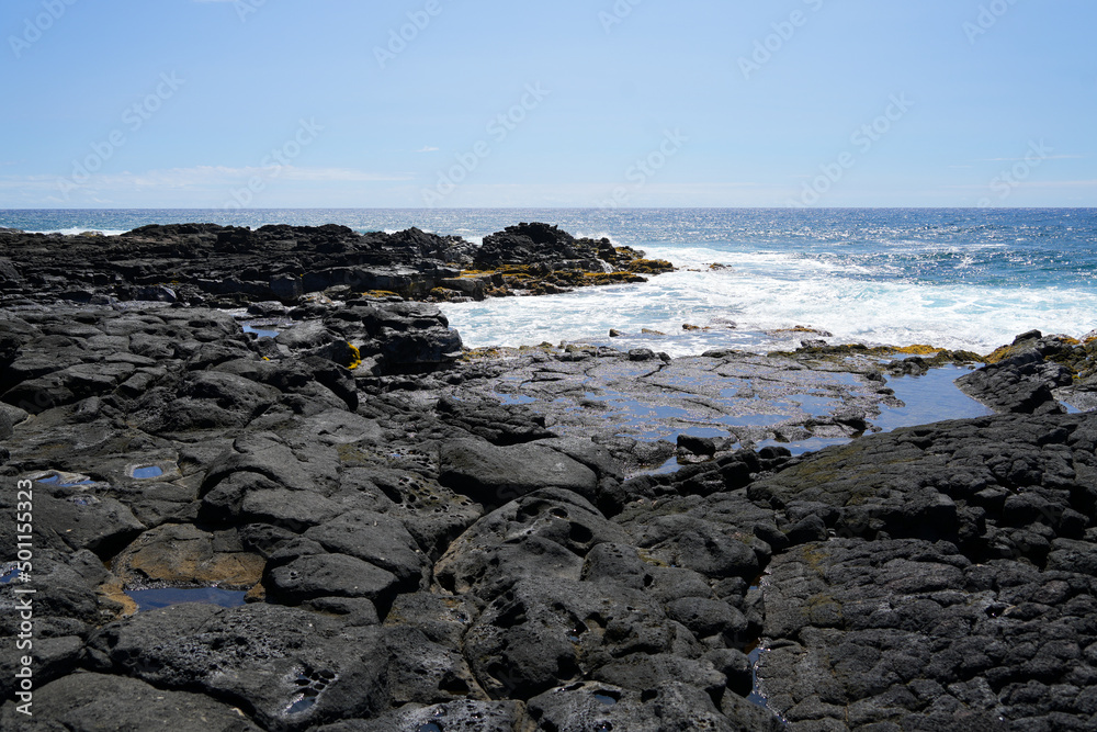 Waves crashing on the lava rocks of South Point Park, the southernmost point of the United States on the Big Island of Hawaii in the Pacific Ocean