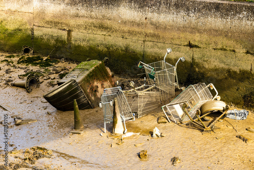 A collection of abandoned shopping trollies, traffic cones, a tyre and a large bin, in the mud beside the River Medway in Strood/Rochester.   photo