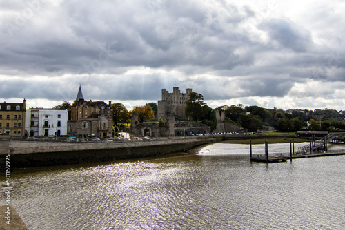 Rochester Castle, from the bridge across the Medway River.  Storm clouds were gathering but the sun was still shining.  Sunbeams are seen through the clouds.  October 2021.