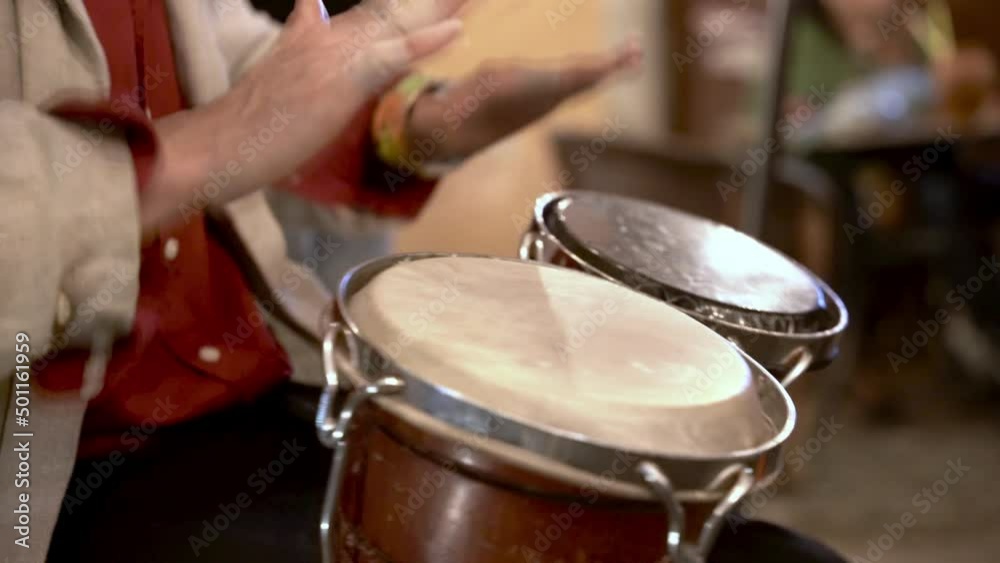 A man playing bongo drums in the street A man playing bongo drums in the street