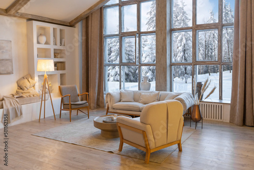 cozy warm home interior of a chic country chalet with a huge panoramic window overlooking the winter forest. open plan  wood decoration  warm colors and a family hearth