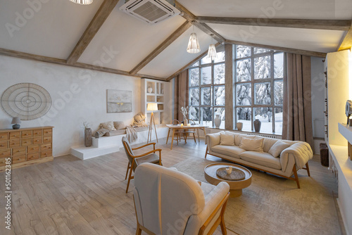 cozy warm home interior of a chic country chalet with a huge panoramic window overlooking the winter forest. open plan, wood decoration, warm colors and a family hearth