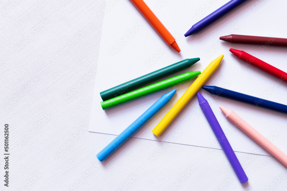 top view of colorful crayons on white paper and textured background. top view of colorful crayons on white paper and textured background.