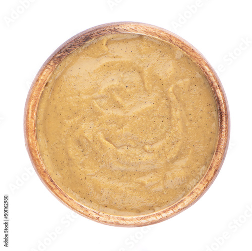 Top view of mustard sauce in a wooden bowl on a white background. organic and natural puree.