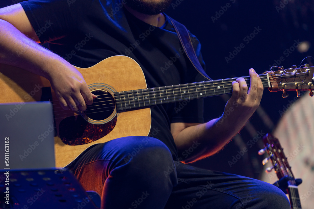 Obraz premium Man playing acoustic guitar on the stage at the concert