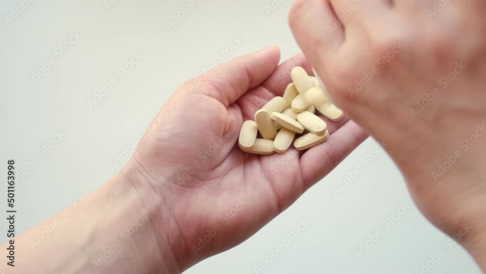 Pills, capsules and drugs pouring from bottle in doctor's hand. Hands spilling tablets. Woman holding medicine, medication. Female taking supplement product or vitamin. Close-up. White background. Pills, capsules and drugs pouring from bottle in doctor's hand. Hands spilling tablets. Woman holding medicine, medication. Female taking supplement product or vitamin. Close-up. White background.