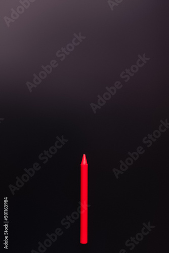 top view of red crayon on black background.