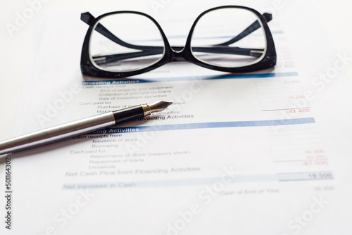 Work desk, documents, pen, glasses on a white table.